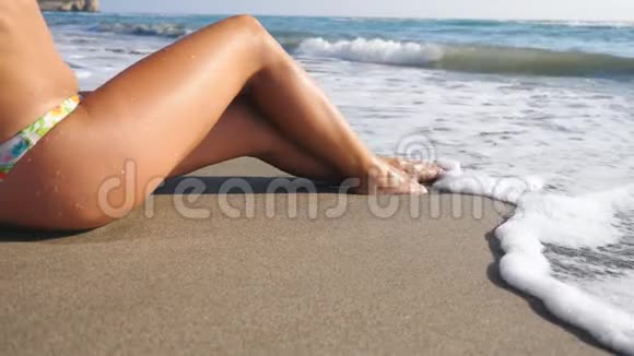 躺在热带海滩上享受假期的女人苗条的腿温暖的海浪冲洗着晒黑的雌性脚女孩视频的预览图