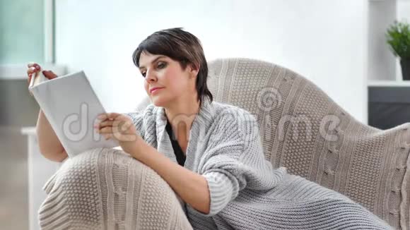 热情的美女独自在温馨的家中阅读有趣的书视频的预览图