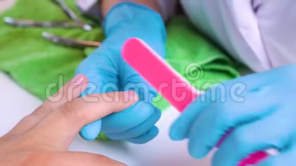 医生在水疗沙龙里给一个男人锯了一个粉红色的指甲文件指甲护理为男性修指甲视频的预览图