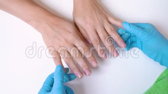 在手套中处理指甲的客户的手和指甲大师的特写用奶油按摩和滋润指甲视频的预览图