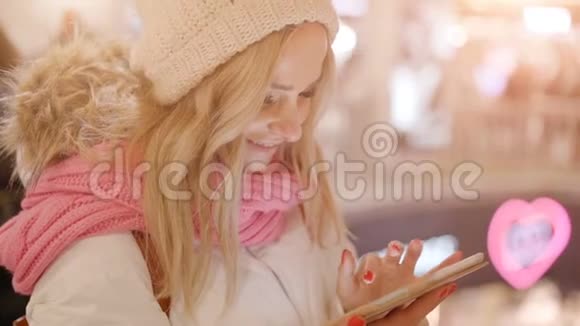 穿冬装的可爱女人在商场里用平板电脑视频的预览图