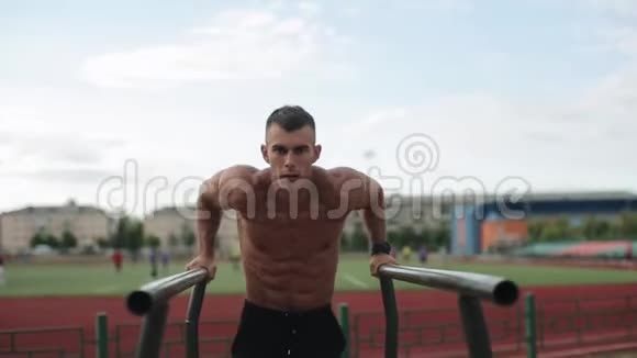 近距离观看一个赤膊肌肉运动员在运动场上做体重俯卧撑模糊的观点视频的预览图
