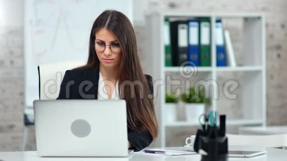 专业的女性市场专家适合在现代光办公室内部使用笔记本电脑视频的预览图