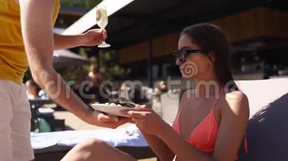服务员在豪华酒店海滩俱乐部为漂亮的女士提供牡蛎扇贝香槟或汽酒视频的预览图