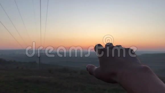 日落天空背景下男性手的特写视频的预览图