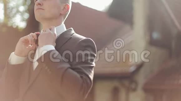 男性手调整蝴蝶结特写年轻人摸着白色衬衫上的时髦圆点蝴蝶结领带视频的预览图