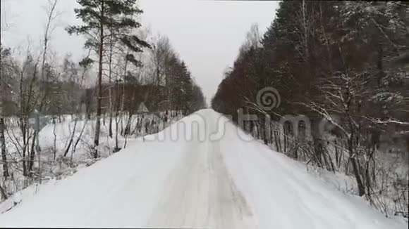 蓝老复古车在林中冬季乡间小路上行驶空中观景台视频的预览图