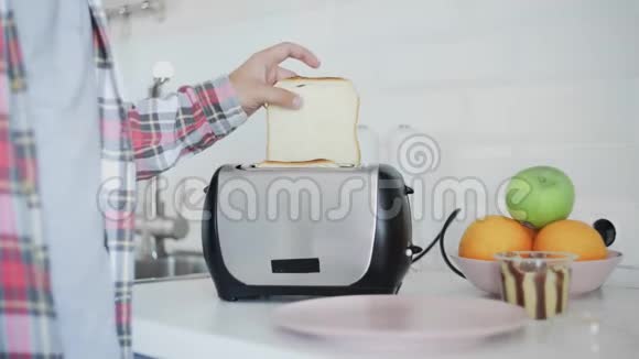 一个人把面包放进烤面包机里面包是油炸的早餐食品正在准备中厨房里的电器视频的预览图