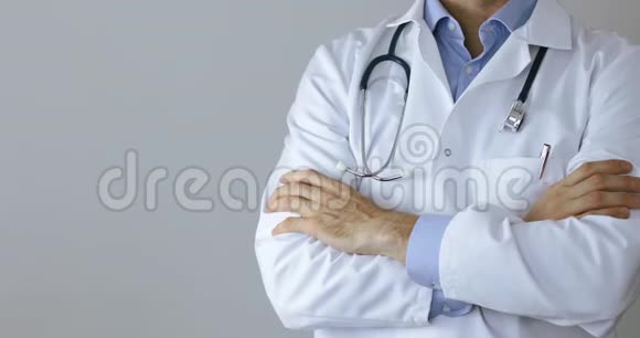 穿着白色外套的医生双臂交叉在灰色背景上视频的预览图