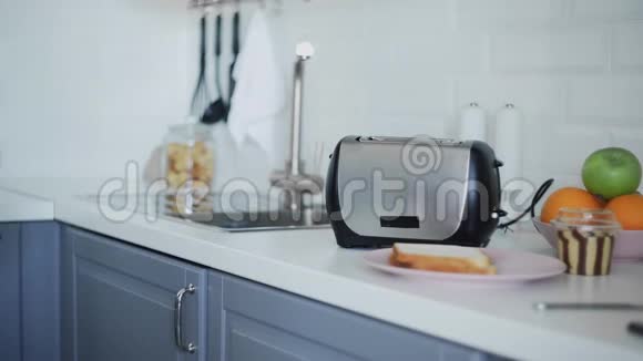 一个人把面包放进烤面包机里面包是油炸的早餐食品正在准备中厨房里的电器视频的预览图