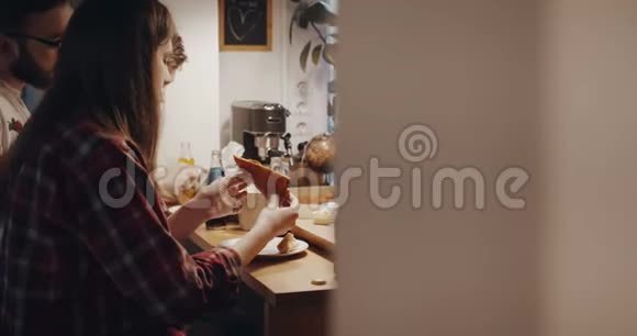 年轻的多民族快乐的男女朋友吃披萨和饮料在家庭厨房聚会上聊天慢动作视频的预览图