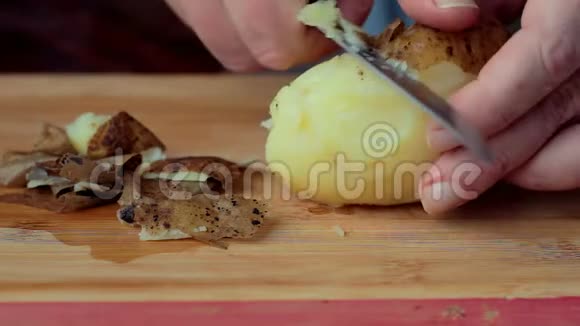 一个男人把煮熟的土豆从皮肤上清洗视频的预览图