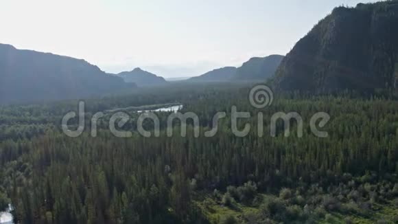 鸟瞰飞行越过森林河流山丘太阳太阳光的反射视频的预览图