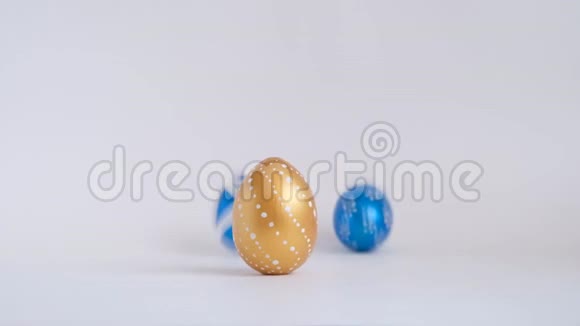 鸡蛋在白色的桌子上滚动互相敲门复活节金色装饰的彩蛋在白色背景上分离最小视频的预览图