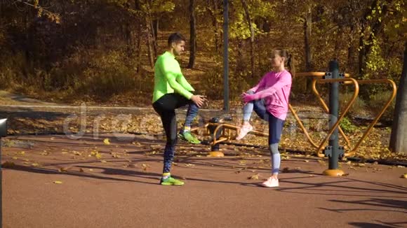 一对运动员在秋日在运动场上热身和伸展双腿视频的预览图
