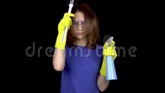 一个年轻的女人用马桶刷梳头发戴安全眼镜和带清洁工具手套的女人视频的预览图