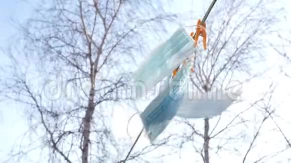 蓝色的医用口罩挂在晾衣绳上晾衣架顶着天空白桦树视频的预览图