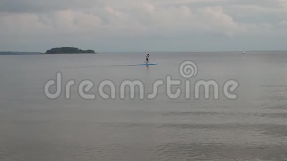 一位年轻的女运动员正在冲浪它漂浮在海面上的地平线上多云天气伴有雷声视频的预览图