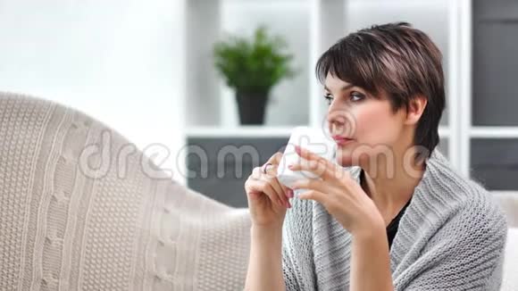 穿暖和毛衣的漂亮成熟女性在家中喝茶放松中等特写视频的预览图