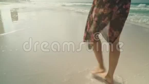 在夏天的海滩上年轻女子沿着海水和沙子散步闭上双腿旅行概念视频的预览图