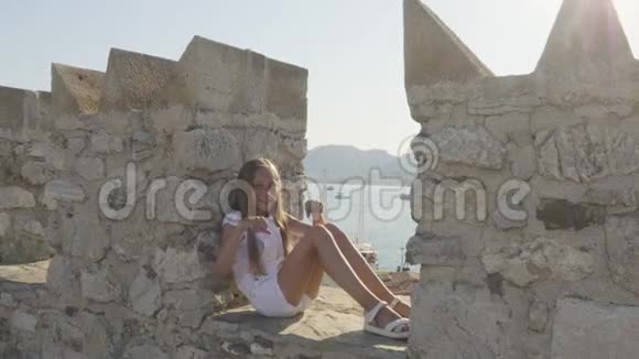 快乐的女孩坐在石墙上跳舞视频的预览图