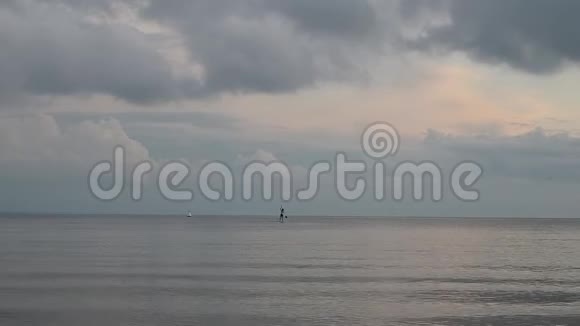 一位年轻的女运动员正在冲浪它漂浮在海面上的地平线上多云天气伴有雷声视频的预览图