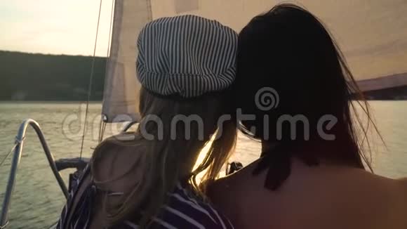 日落时女孩们坐在帆船旁视频的预览图