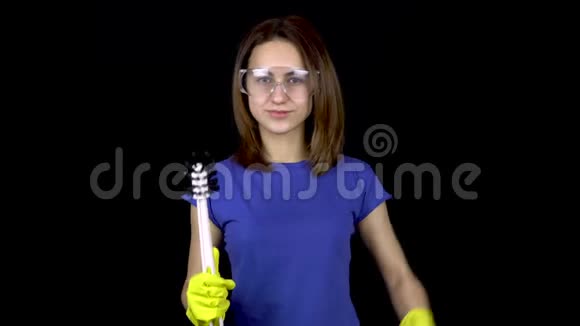 一个年轻的女人正在用马桶刷到厕所并显示二头肌戴安全眼镜和带工具手套的女人视频的预览图