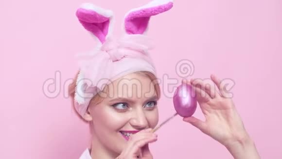 性感的女人与面具复活节兔子在粉红色的背景看起来非常性感猎蛋和画蛋视频的预览图