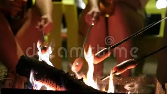 一群人在火上烤火棒上烤香肠让他们放松视频的预览图