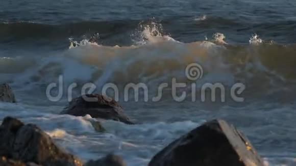 夕阳下海浪拍打着海岸上的岩石视频的预览图