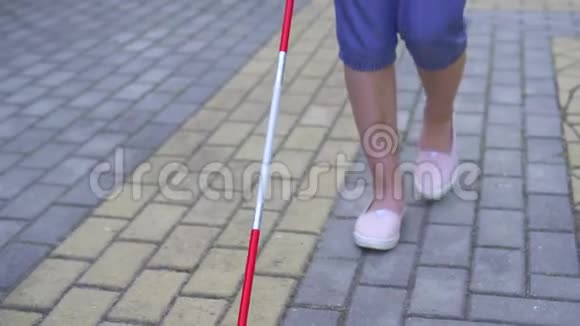 一位带着拐杖的亚洲视障年轻女子正在公园里慢慢地靠近视频的预览图