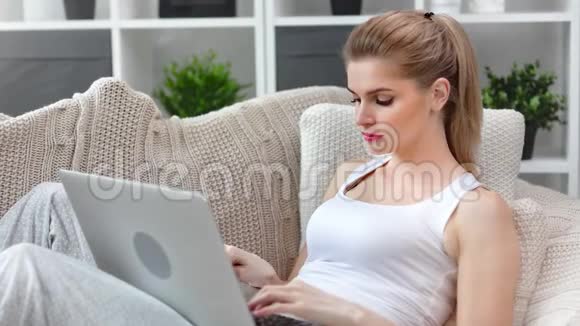 可爱的忙碌的微笑的年轻女孩用手提电脑打字键盘上有积极的情绪视频的预览图