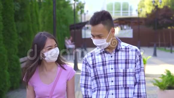 两个戴着医用口罩的年轻亚洲学生走在街上和慢莫说话视频的预览图