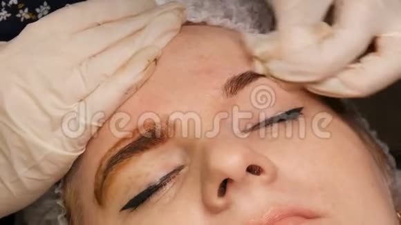美容师用一张特殊的餐巾纸从眉毛的皮肤上移除色素的残留视频的预览图