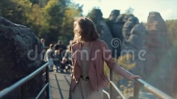 慢动作近景美丽的年轻女子走在山上的铁路上在手机上自拍视频的预览图