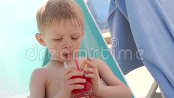 夏天一个金发小男孩在泳池边喝鸡尾酒视频的预览图