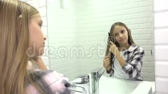 孩子在镜子里梳头孩子在浴室里梳头金发女孩梳头视频的预览图
