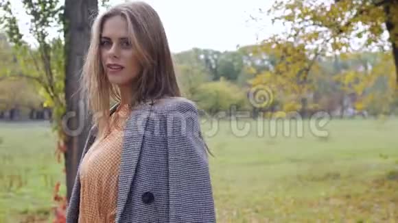 漂亮的黑发女孩站在秋天的公园里环顾四周穿格子夹克的白种人美女视频的预览图