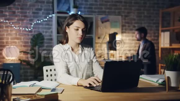 精疲力竭的女士用笔记本电脑打字然后晚上躺在办公室工作的椅子上视频的预览图
