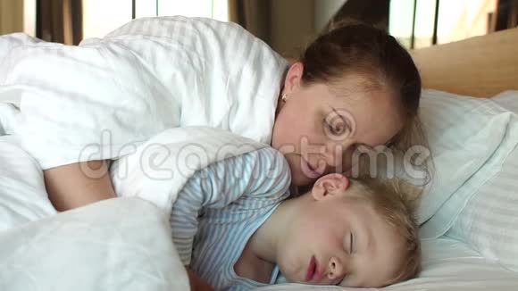 母亲早上在床上叫醒她的孩子儿子睡在毯子下面视频的预览图