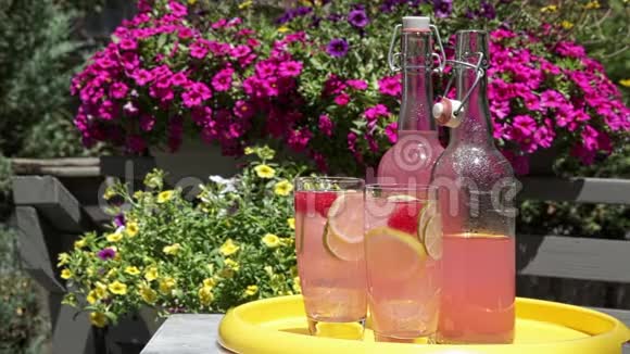 在阳光下托盘上放着柠檬柠檬和覆盆子的粉红色柠檬水视频的预览图