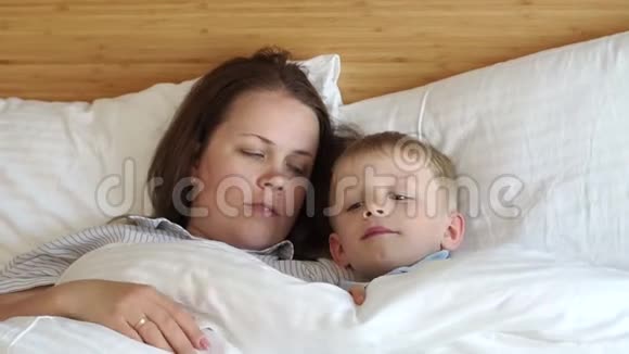 母亲和儿子躺在床上的枕头上他们用毯子盖着视频的预览图