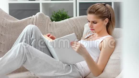 美丽的平静女性格子阅读书在舒适的家庭内部中镜头视频的预览图