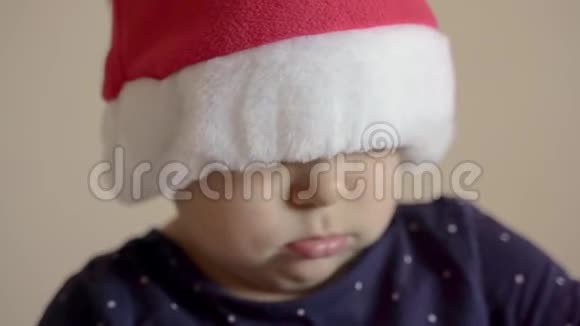 在圣诞老人的红帽子里特写婴儿肖像脸上严肃的表情有趣的孩子视频的预览图