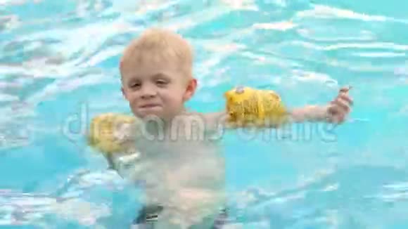 带着充气套的小男孩在室外的游泳池里游泳视频的预览图