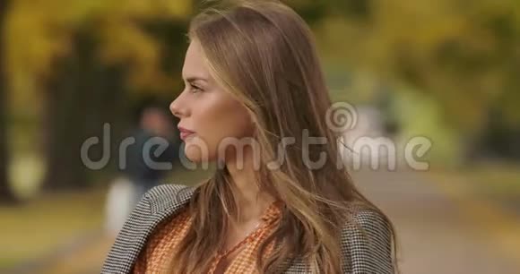 美丽的高加索女人站在秋天公园微笑的肖像穿着格子夹克的迷人女孩视频的预览图