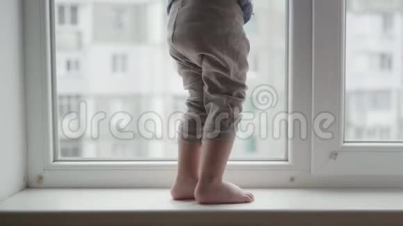 冒着生命危险孩子们的腿走在窗台上一个小男孩在窗户附近有危险视频的预览图