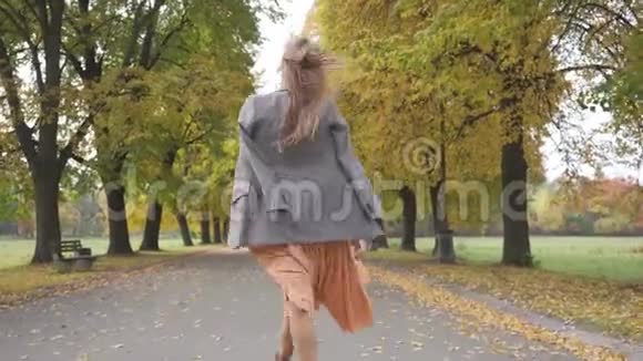 一位身材苗条的高加索女人穿着格子夹克和芥末裙在秋天公园散步少女视频的预览图