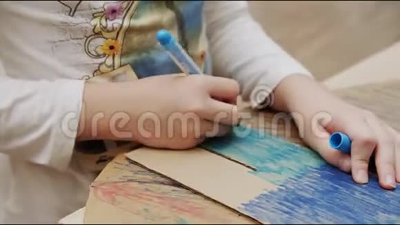 女孩在桌上用蓝色记号笔画纸板图形视频的预览图